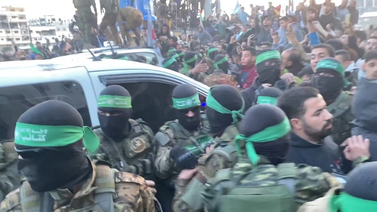 Hamas terrorists emerge in a show of strength escorting Red Cross vehicles carrying 3 Israeli hostages to be released as part of the cease-fire deal. 