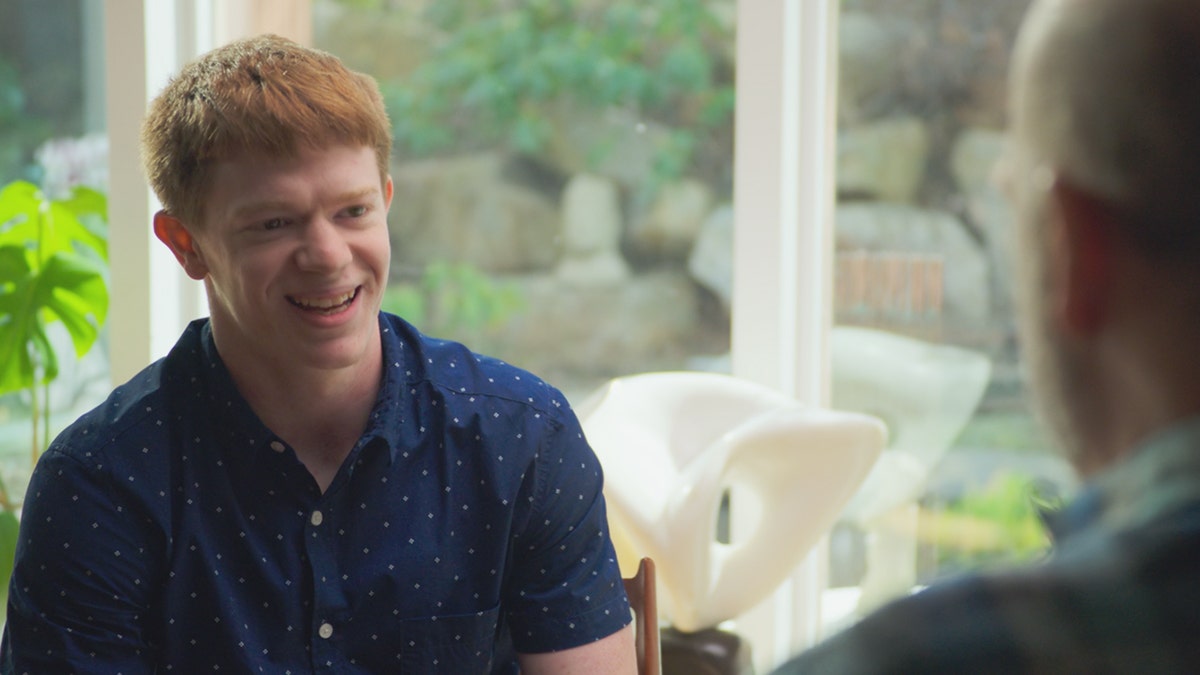Tyler VanScyoc smiling as he sits and talks to a man off camera.
