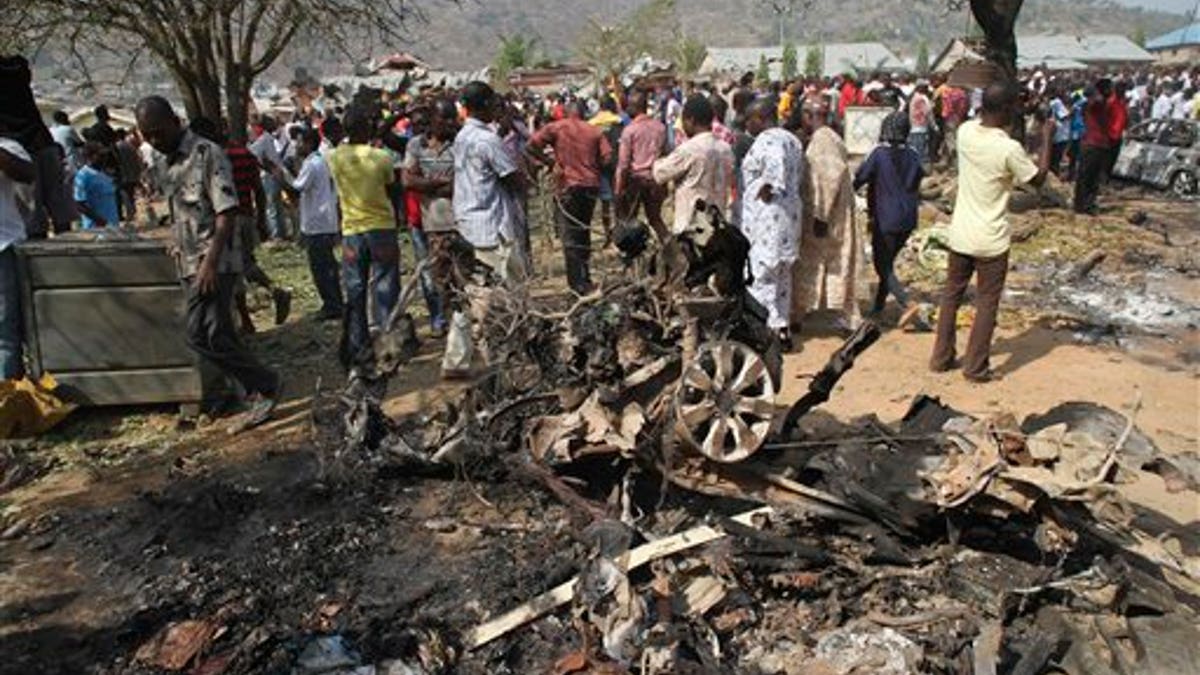 Dec. 25, 2011: Onlookers gather around a car destroyed in a blast next to St. Theresa Catholic Church in Madalla, Nigeria after an explosion ripped through a Catholic church during Christmas Mass near Nigeria's capital.