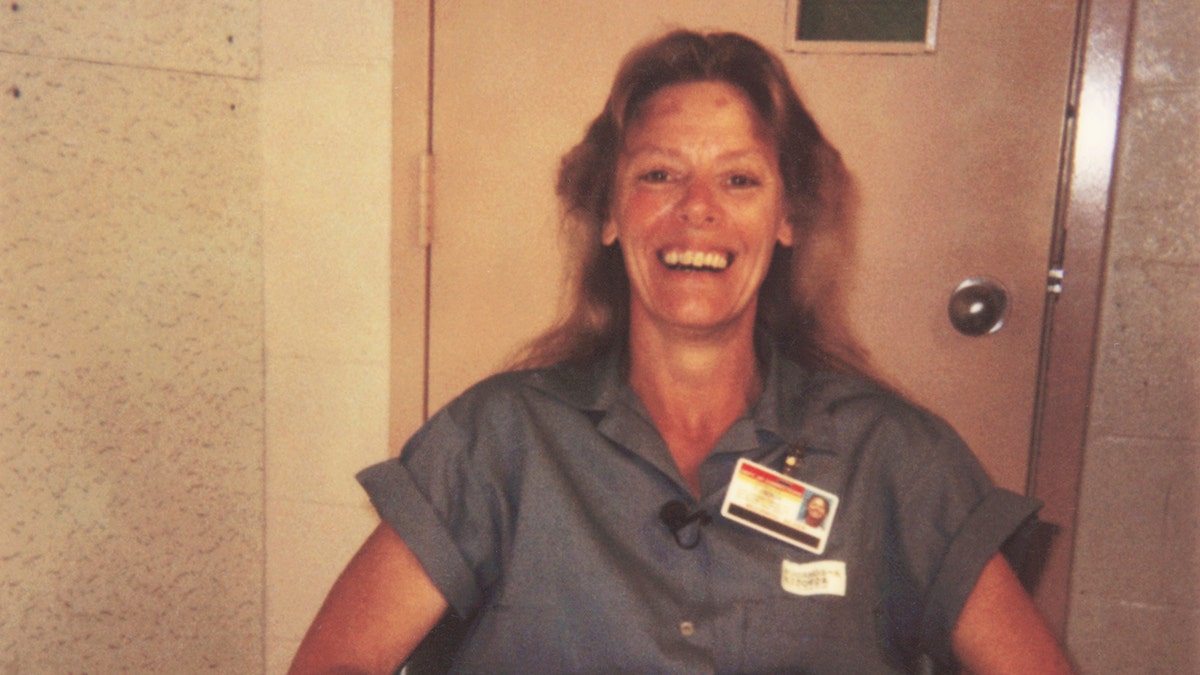 Aileen Wuornos smiling in her blue jumpsuit.