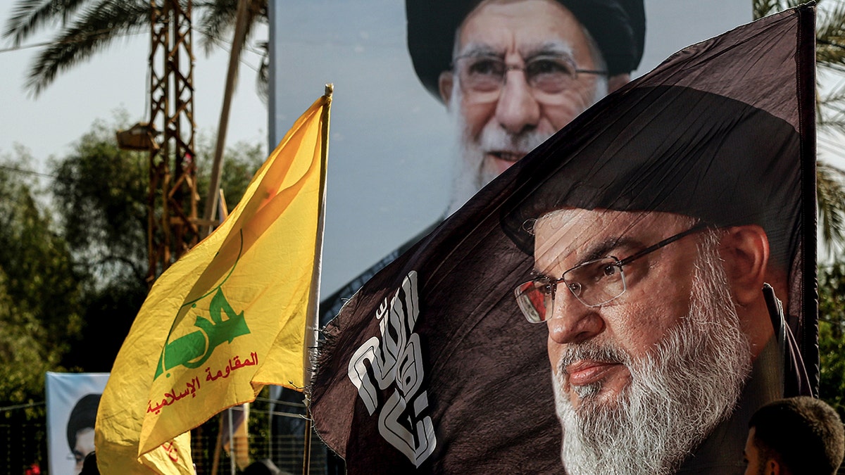 A poster showing Iranian Supreme Leader Ali Khamenei is displayed in Beirut, below a flag bearing the image of assassinated Hezbollah leader Hassan Nasrallah.