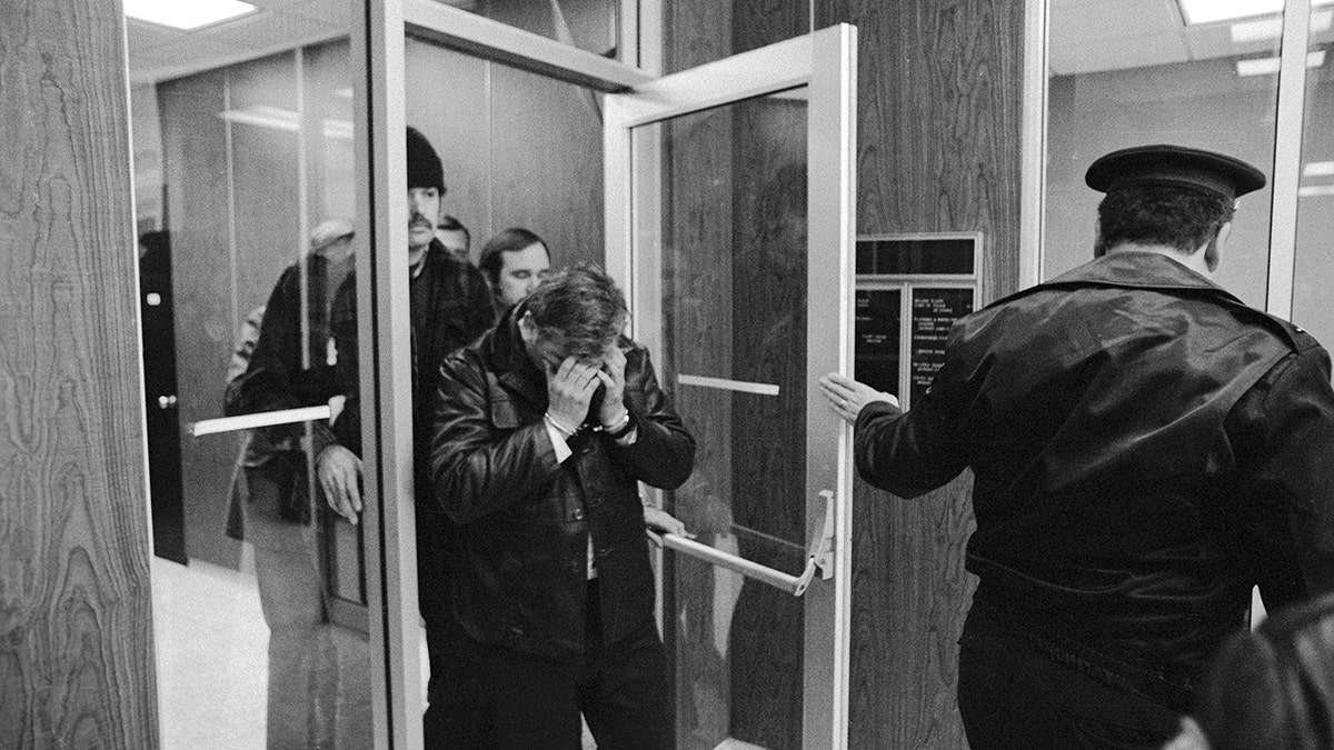 John Wayne Gacy covering his face.