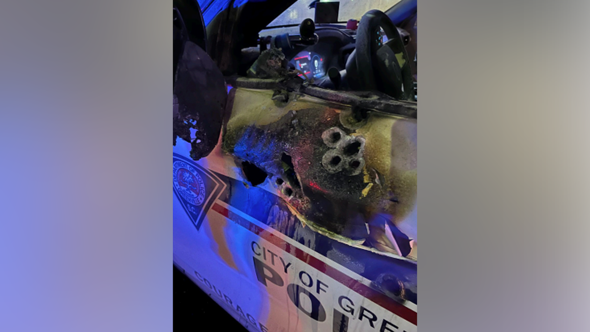 Another view shows bullet damage to a Greenville police patrol vehicle after a shooting