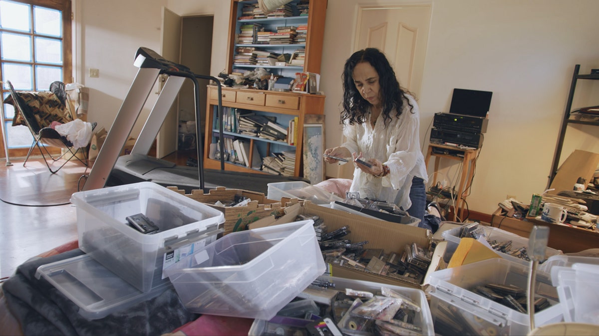 Laura Greenberg looking through boxes of tapes and letters in her home.