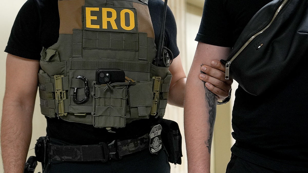 A ICE officer detains a man