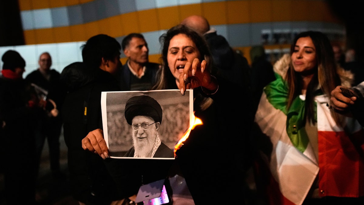 Woman burns a picture of Iran's dictator during protest