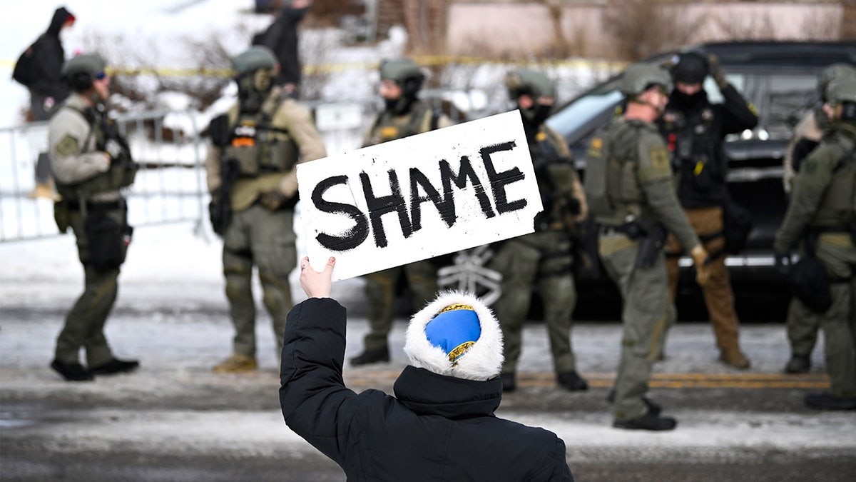 An onlooker holds a sign reading