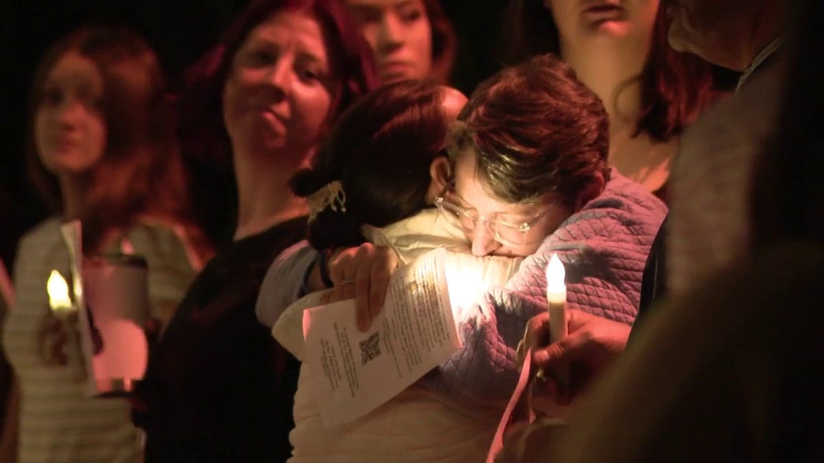 Mourners hug during a candlelight vigil