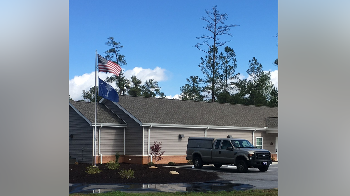 The exterior of the Oconee County Coroner’s Office building with flags displayed outside
