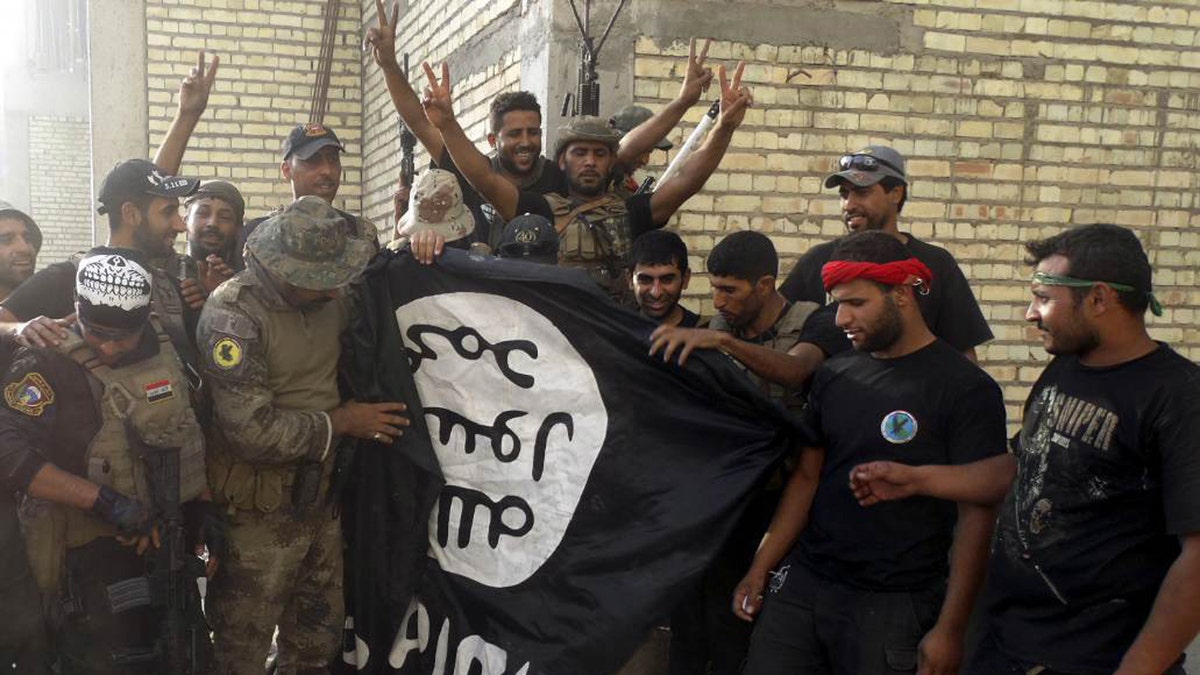 Iraqi security forces pose with ISIS flag which they pulled from University of Anbar on July 26, 2015. Forces clashed with ISIS militants inside the compound.