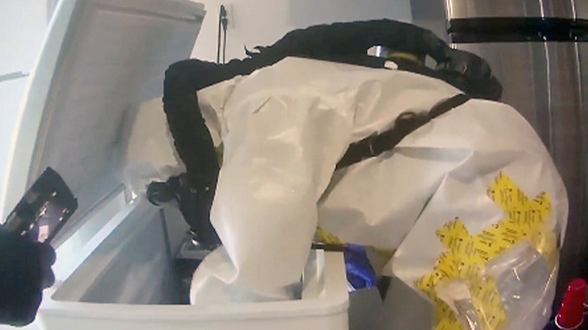 A worker in a hazmat suit searches through material found at the Las Vegas house.