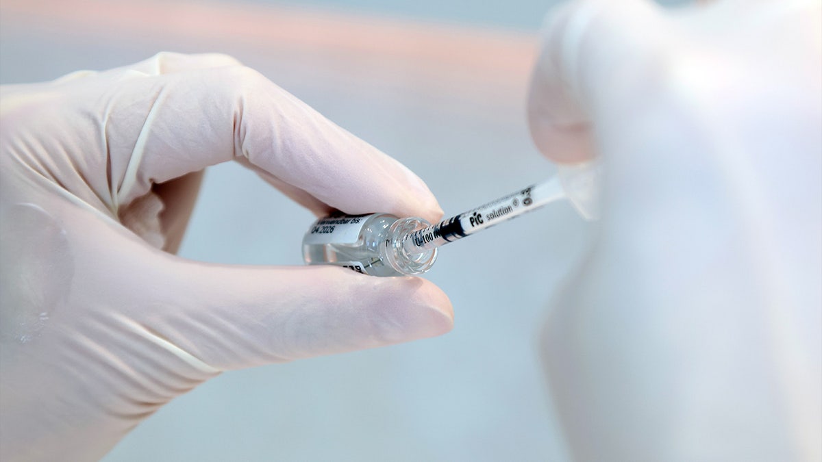 A doctor draws botox with an injection syringe