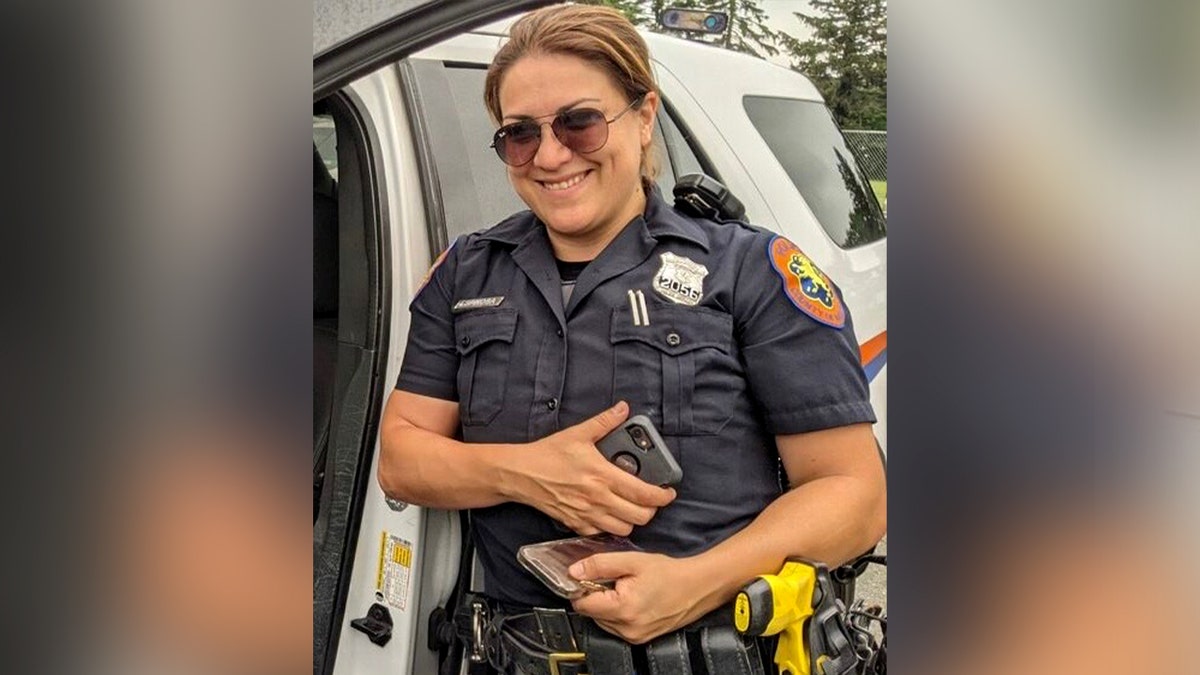 Officer Patricia Espinosa stands beside a police vehicle while on duty.