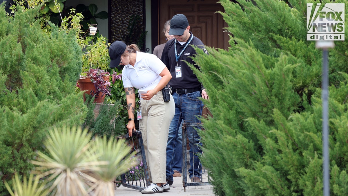 Law enforcement walking through small gate in front of home