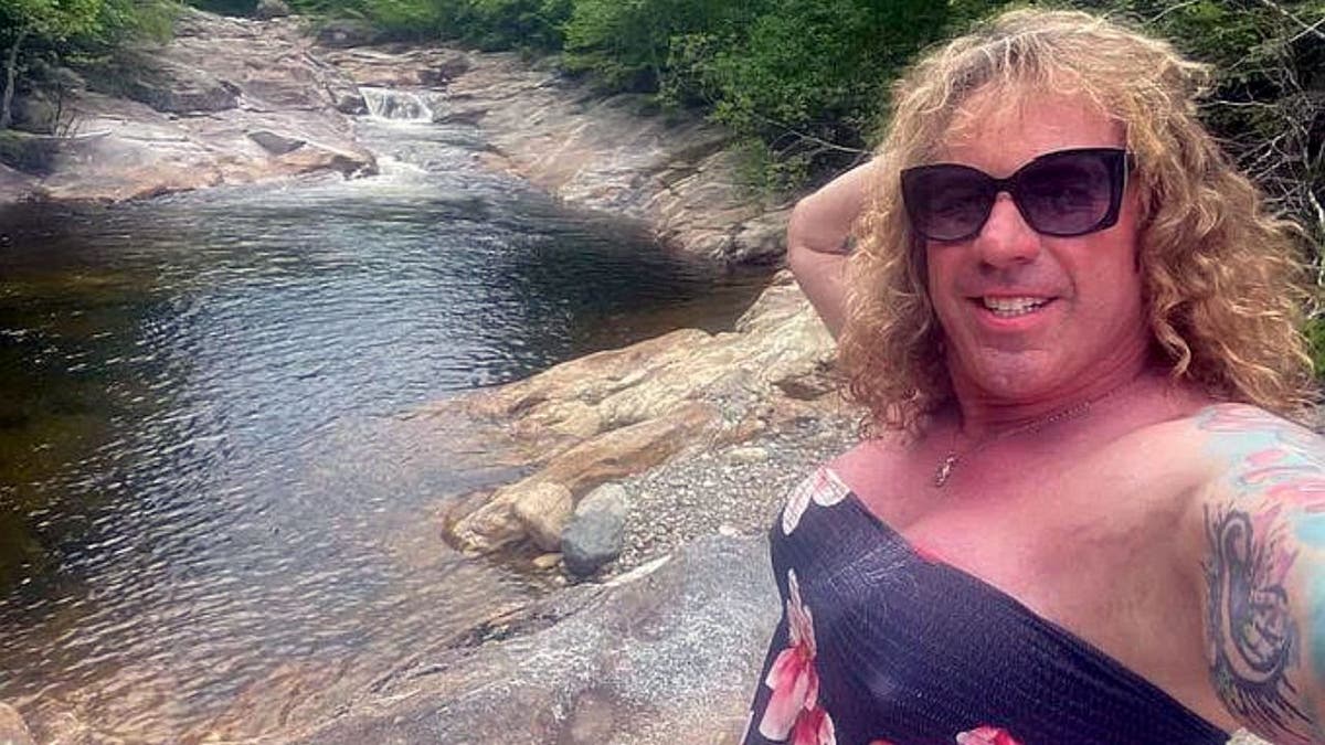 Robert Dorgan, suspect in Rhode Island ice rink shooting, posing outdoors near a rocky stream.